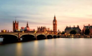 Scenic view of Big Ben and Westminster Bridge over the Thames River at sunset in London, UK.