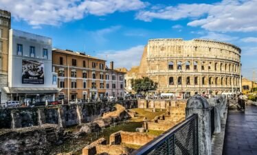 Daylight view of the historic Colosseum in Rome with vibrant city buildings.