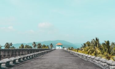 an empty road with a white building in the distance