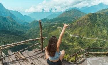 woman raising hand on mountain top