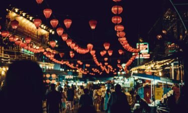 people walking between food stalls under chinese lanterns